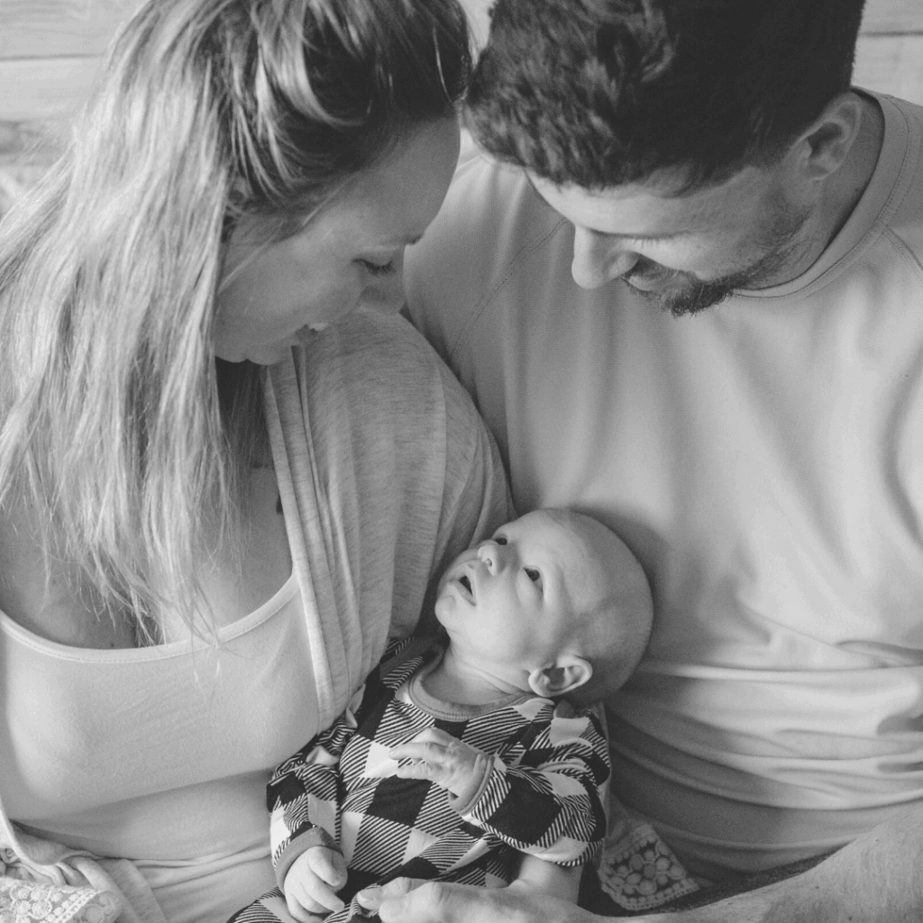 mamma and daddy holding baby boy while staring at each other healthfully rooted home