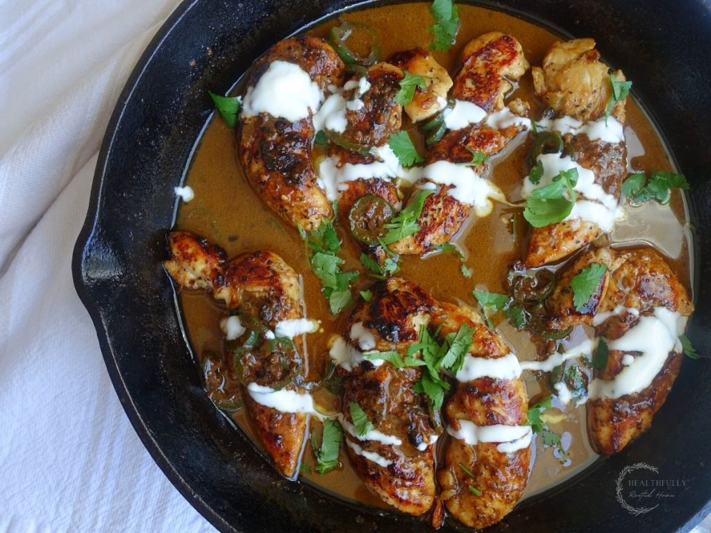 honey jalapeno chicken tenders in a cast iron skillet with honey cream sauce and cilantro on top