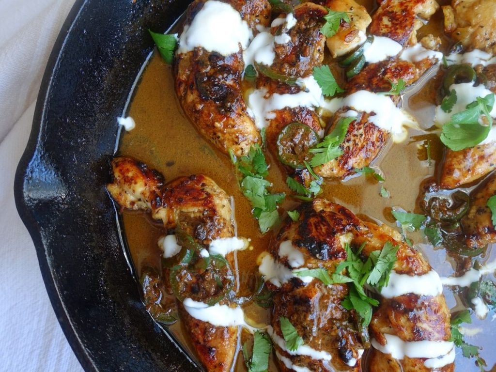 chicken tenders in a sweet and spicy sauce with cream drizzled overtop and garnished with cilantro