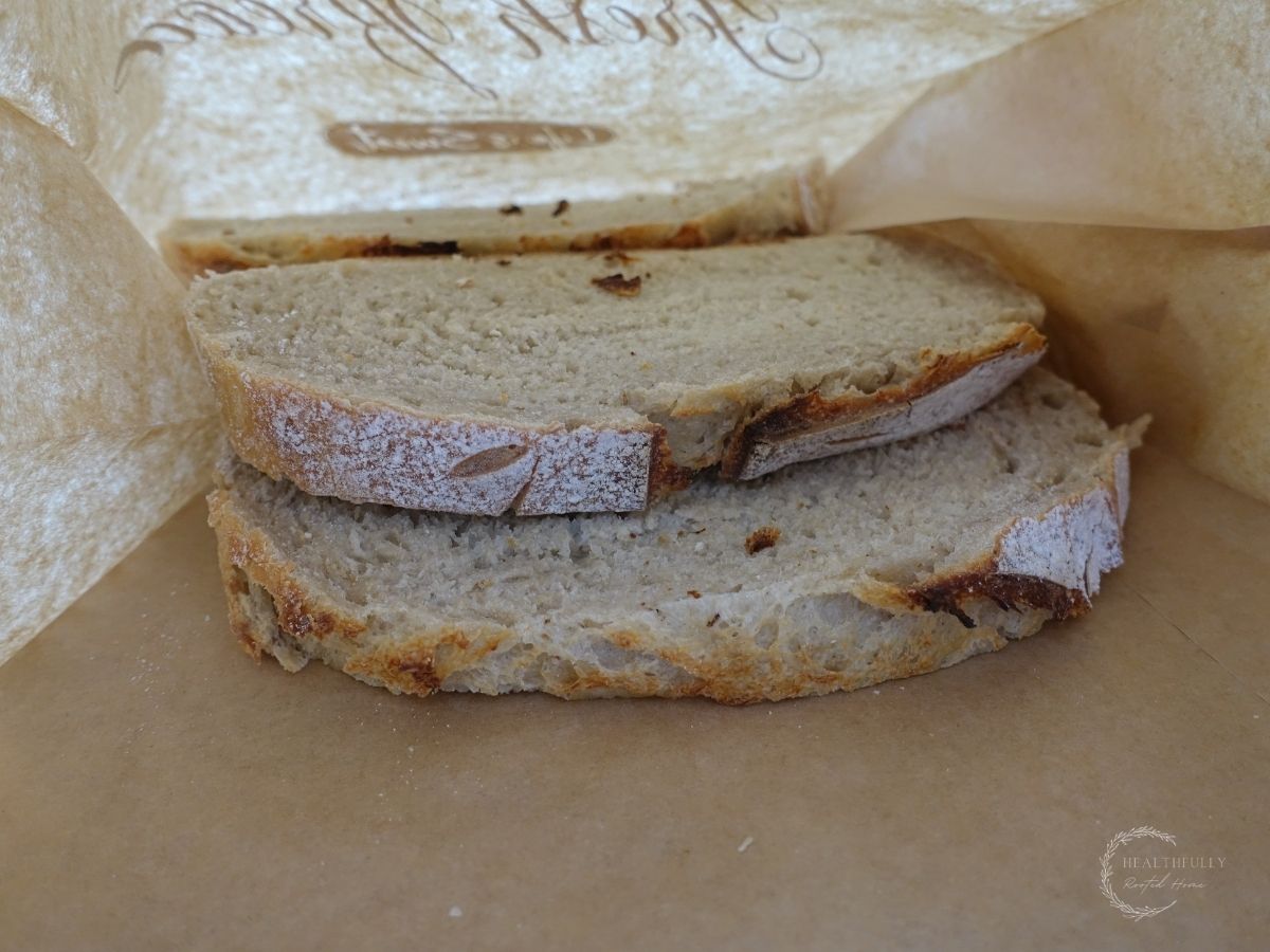partially frozen slices of sourdough bread in a brown paper bag about to go into the freezer bag