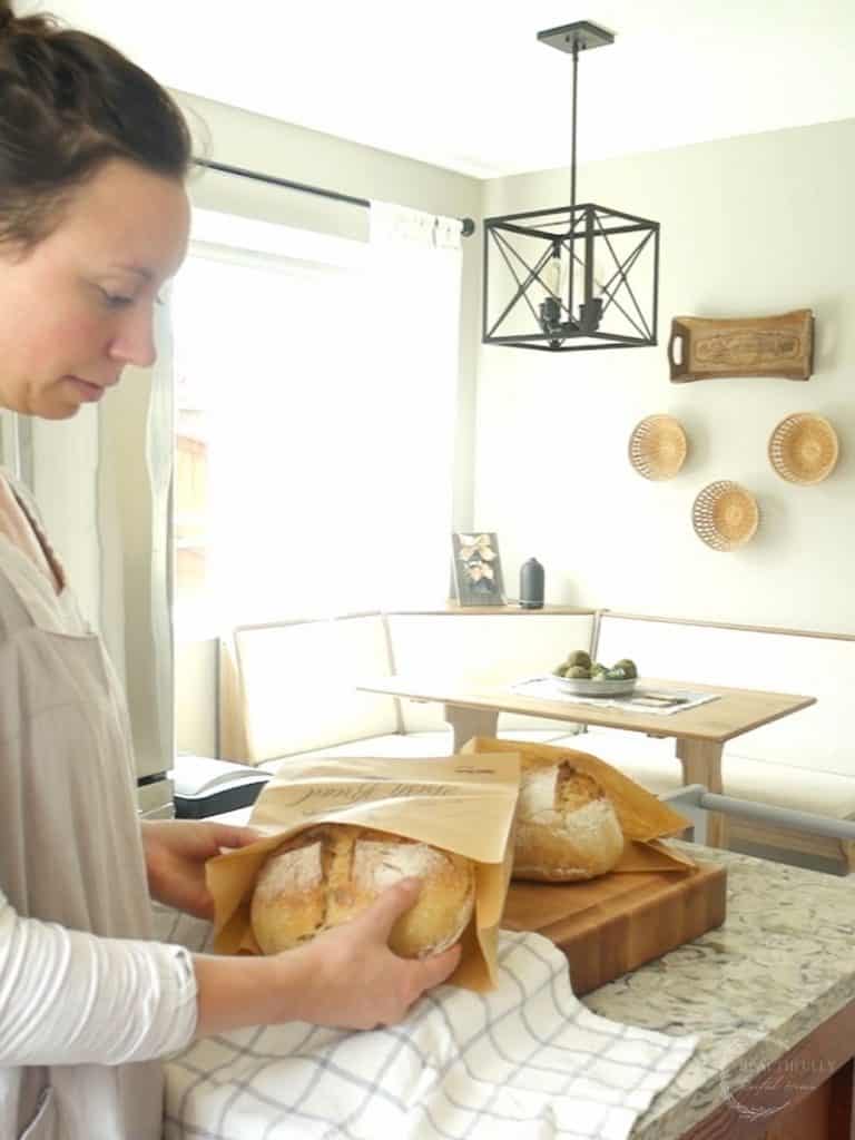 kyrie with healthfully rooted home wearing an apron storing sourdough bread in a brown paper bag