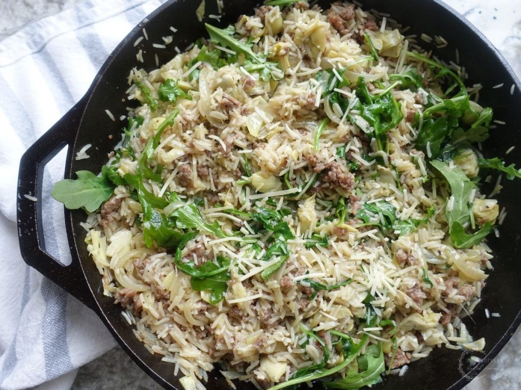 risotto basmati in a cast iron skillet next to a blue and white ticking stripe towel