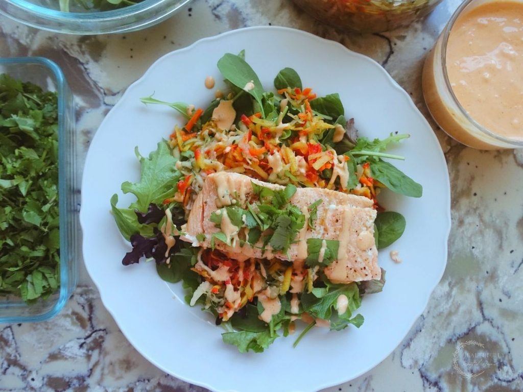 salmon banh mi salad on a white plate with ingredients surrounding it