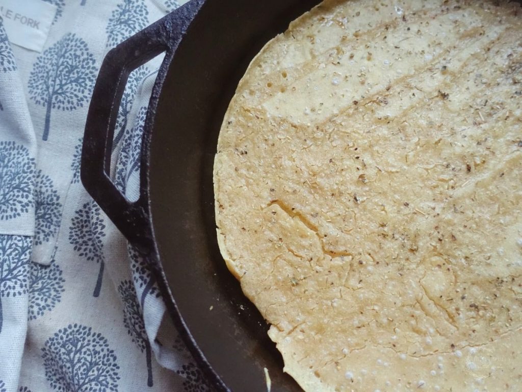 same day sourdough pizza crust inside of a cast iron skillet with an apron with trees on it