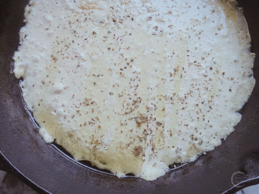 sourdough starter on a cast iron skillet with dried herbs and oil on top
