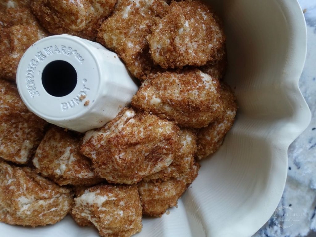 sourdough balls of dough rolled in cinnamon sugar and placed in a bundt pan ready to be baked into monkey bread