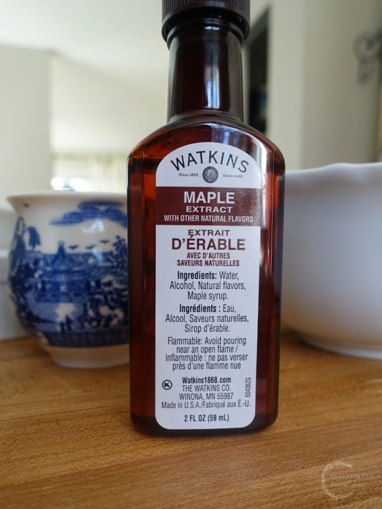 watkins maple extract in an amber bottle in front of a blue and white china bowl and a white bowl