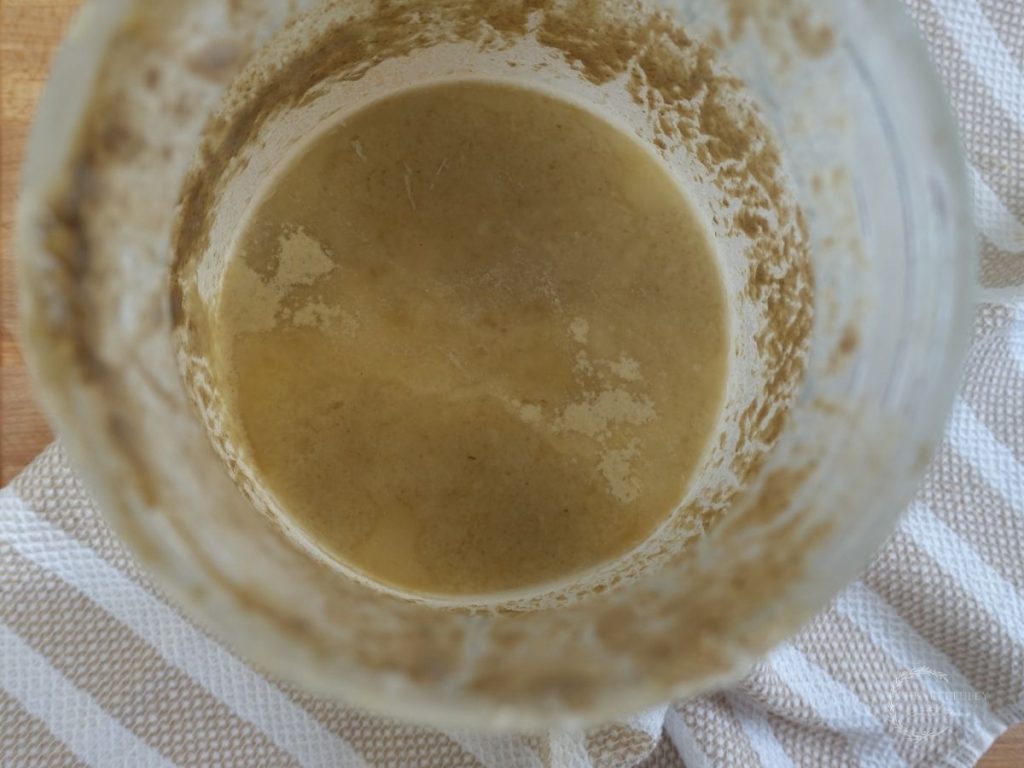 hooch on top of a sourdough starter inside of a glass container indicating this starter still hasnt gone bad beyond repair