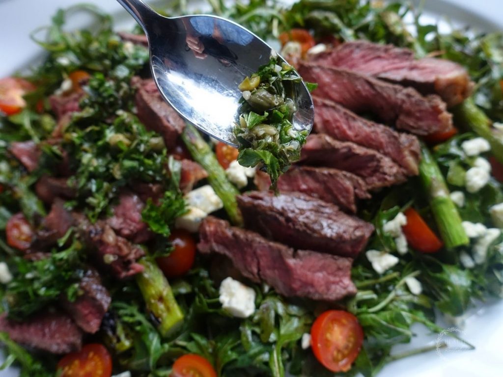 drizzling gremolata over the steak and arugula salad