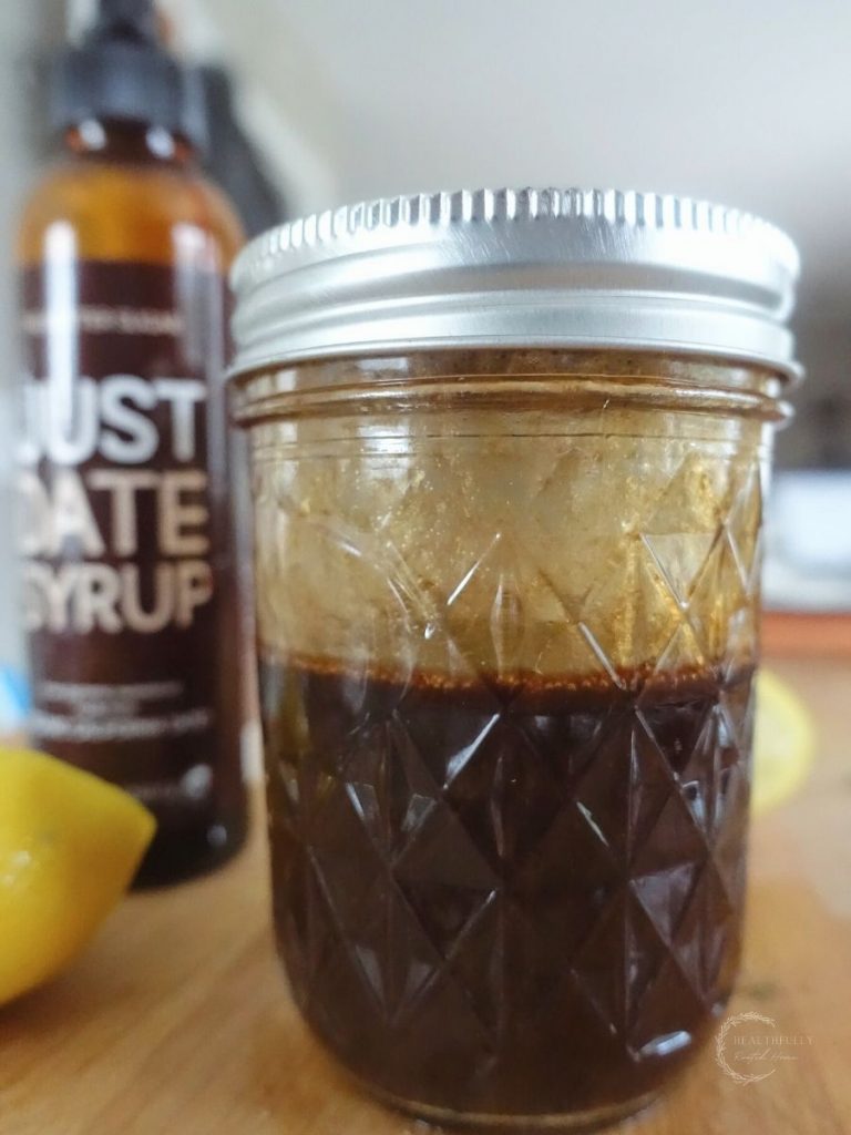 date sweetened balsamic vinaigrette in a mason jar with just date syrup in the background and lemon zest on the side