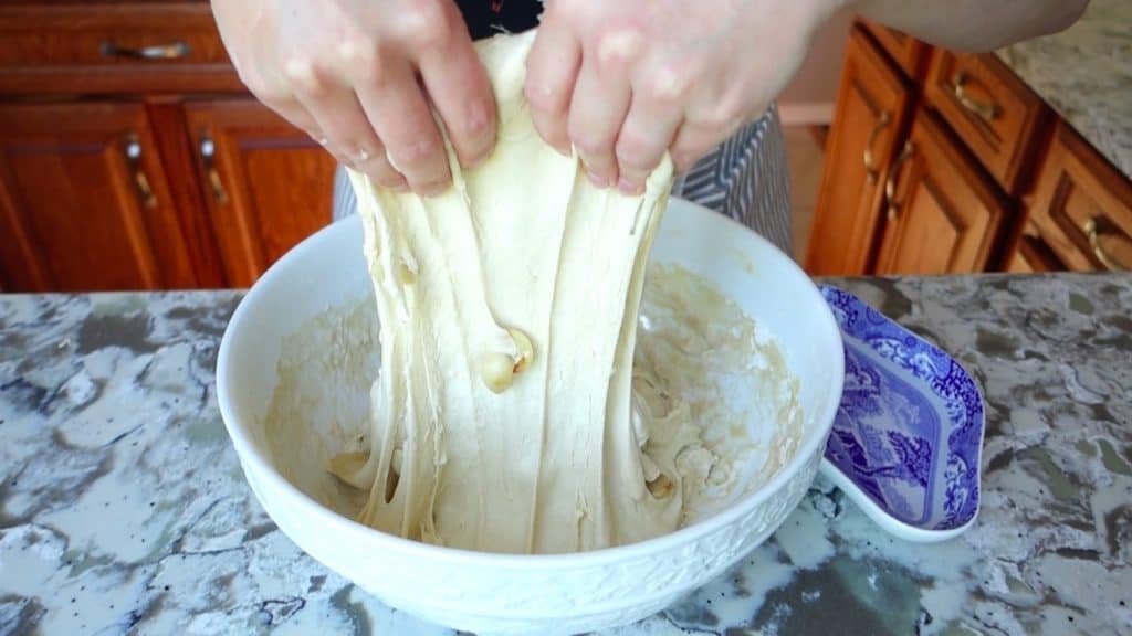 doing a stretch and fold for roasted garlic sourdough lifting dough up