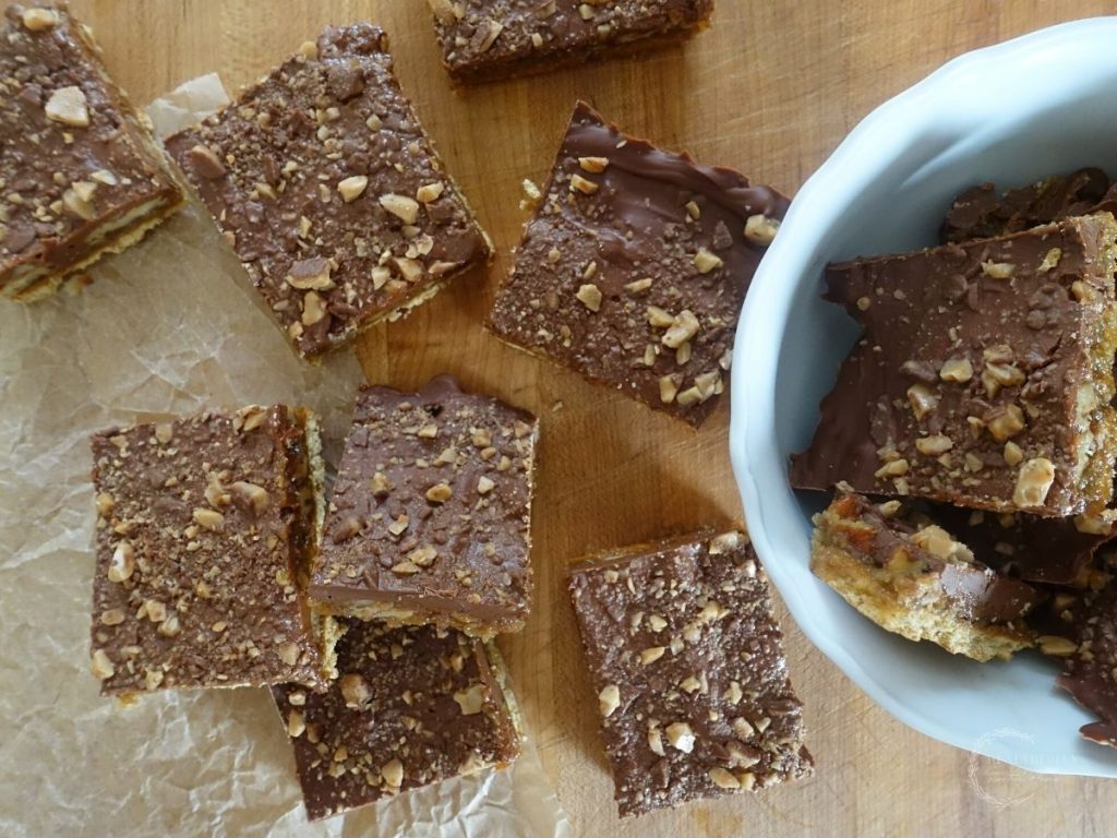 christmas crack with graham crackers scattered on a wooden cutting board with some in a white bowl