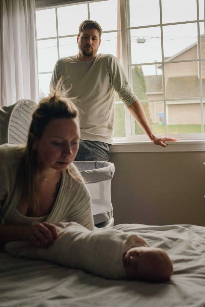 first time parents with their newborn baby on bed