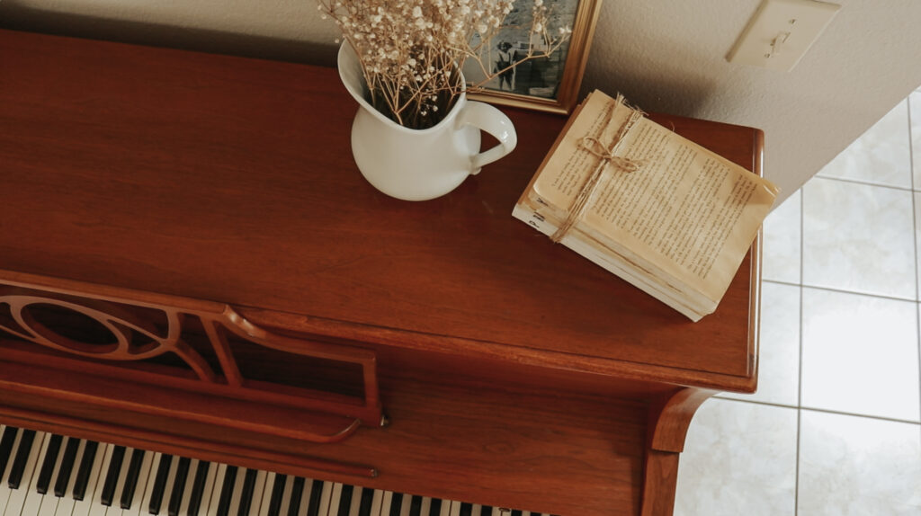 A pretty stack of books and a vase sit on a piano.