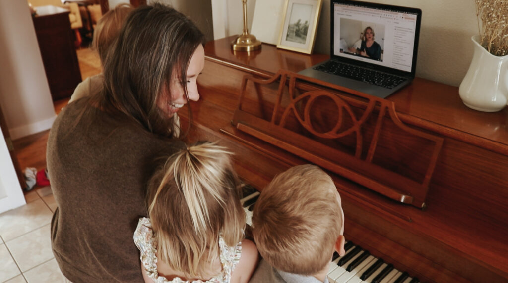 A Christian homemaker smiles at her children as they sit at a piano.